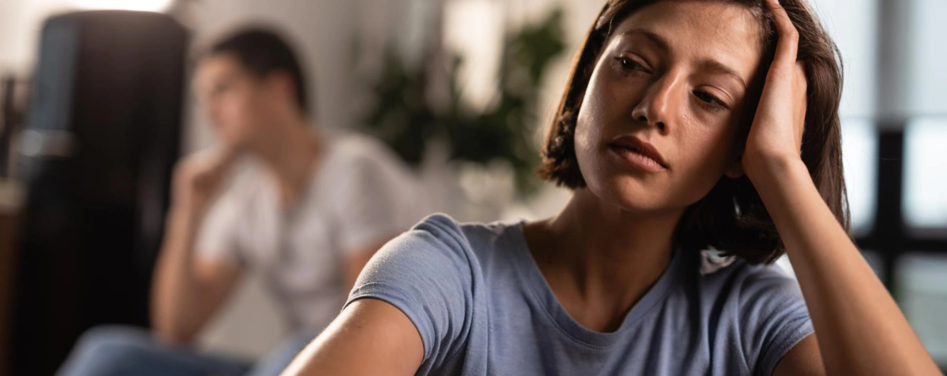 Imagem de um homem chorando com uma mulher ao fundo